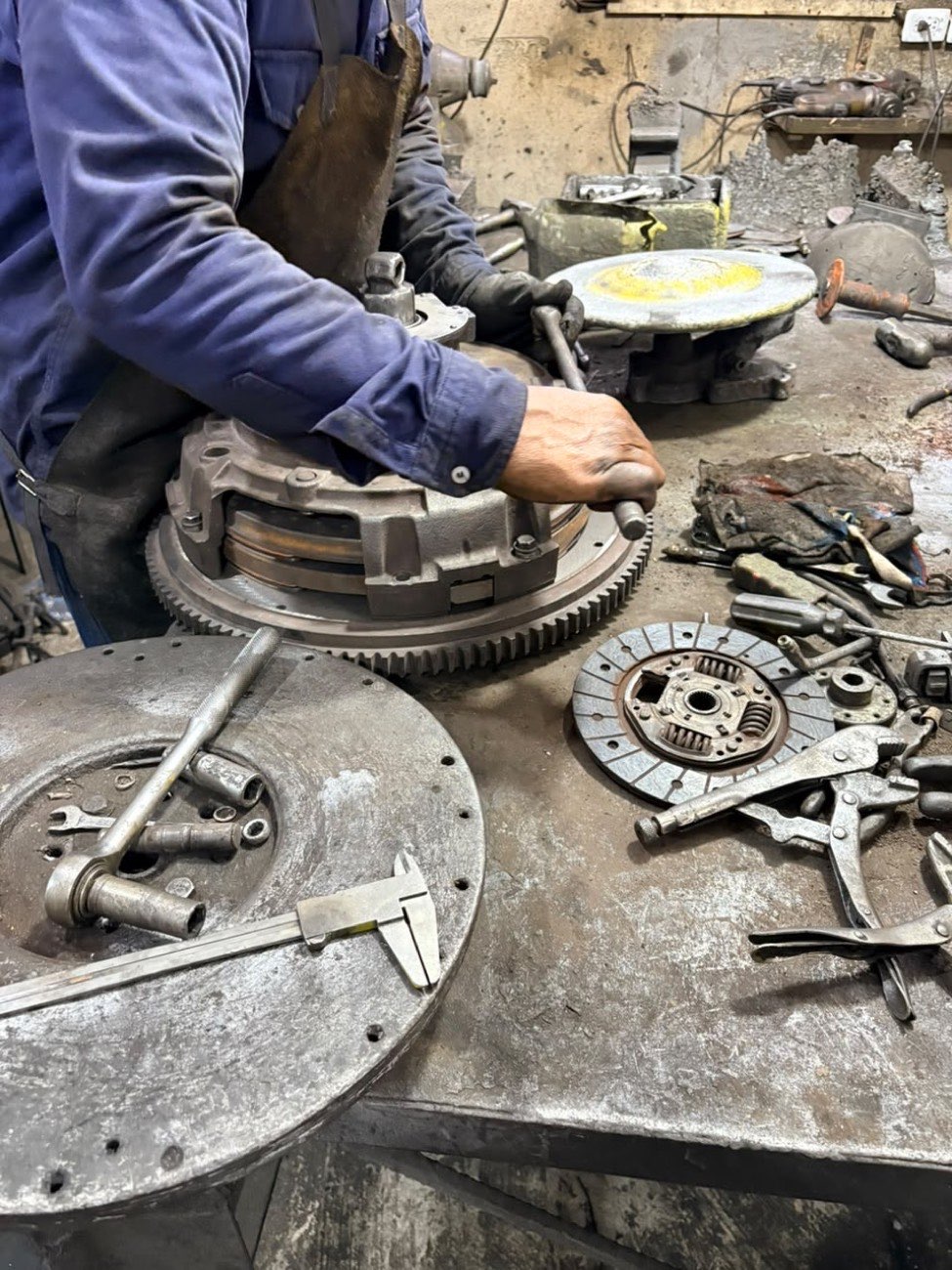 Mecánico ajustando el kit de embrague en el banco de trabajo
